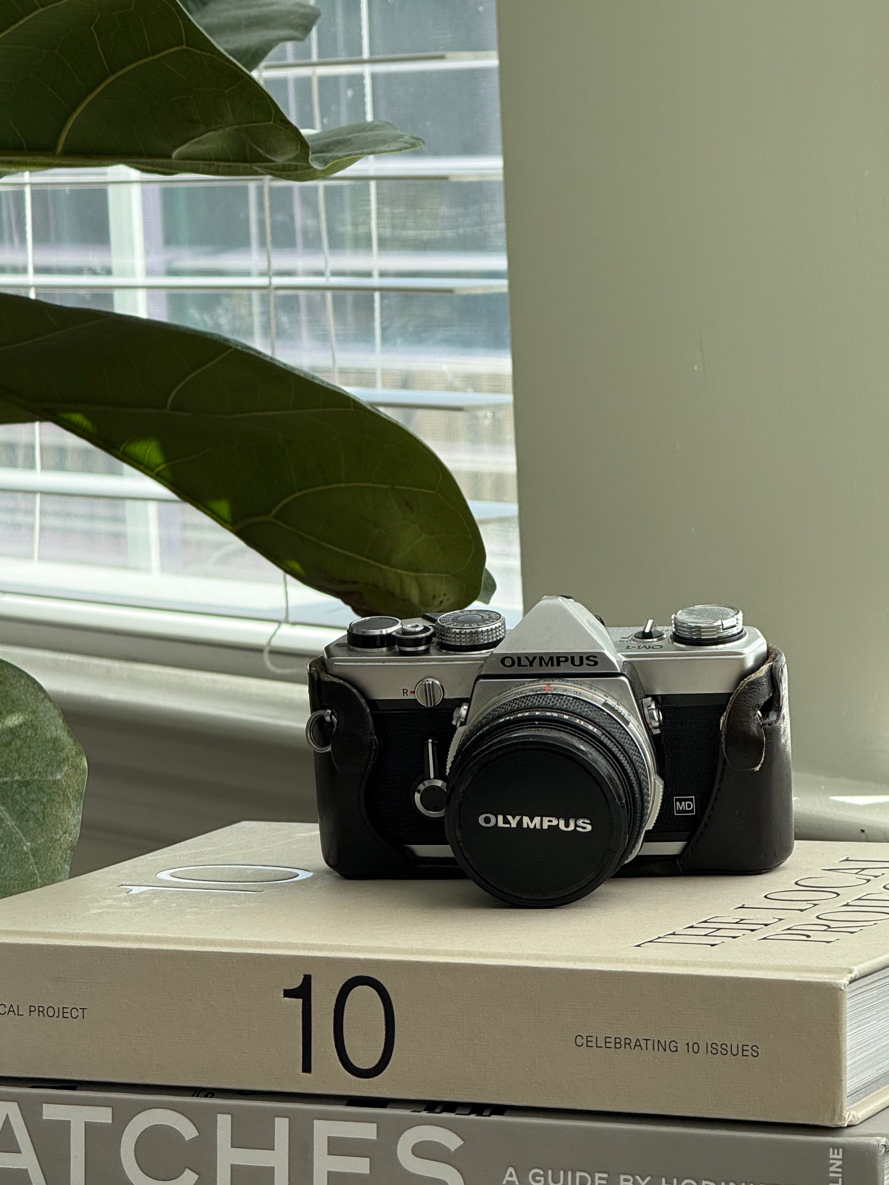 Olympus OM-1 film camera on design books — craft and intentionality