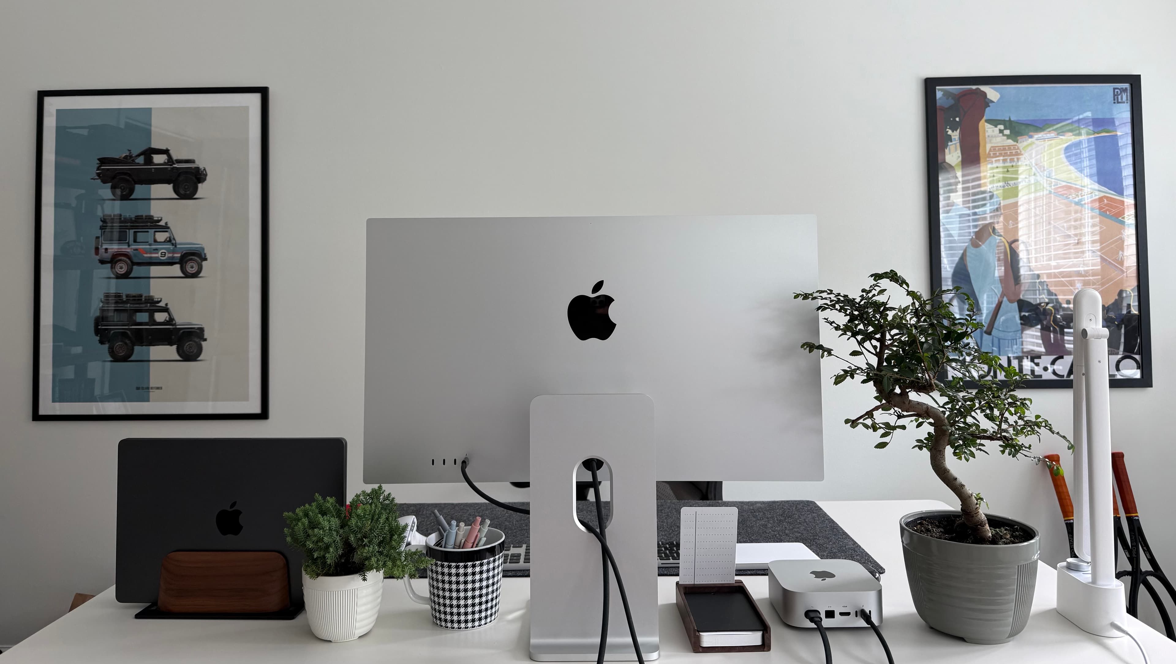 The Maai Services studio — full workspace view with prints, bonsai, Mac Mini cluster, and docked MacBook Pro